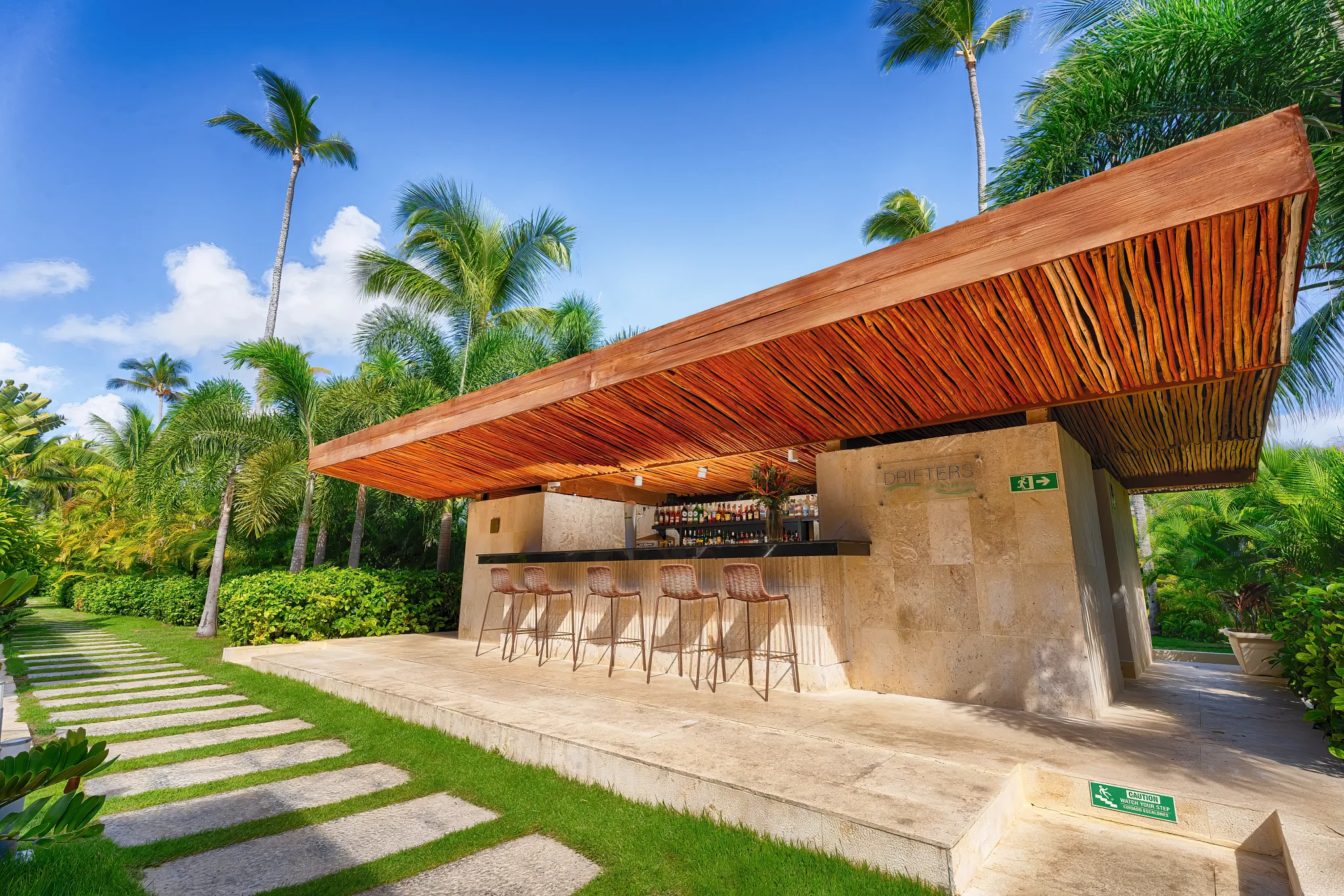 Drifters Lazy River Pool Bar at Secrets Royal Beach Punta Cana featuring a modern open-air bar surrounded by tropical gardens.