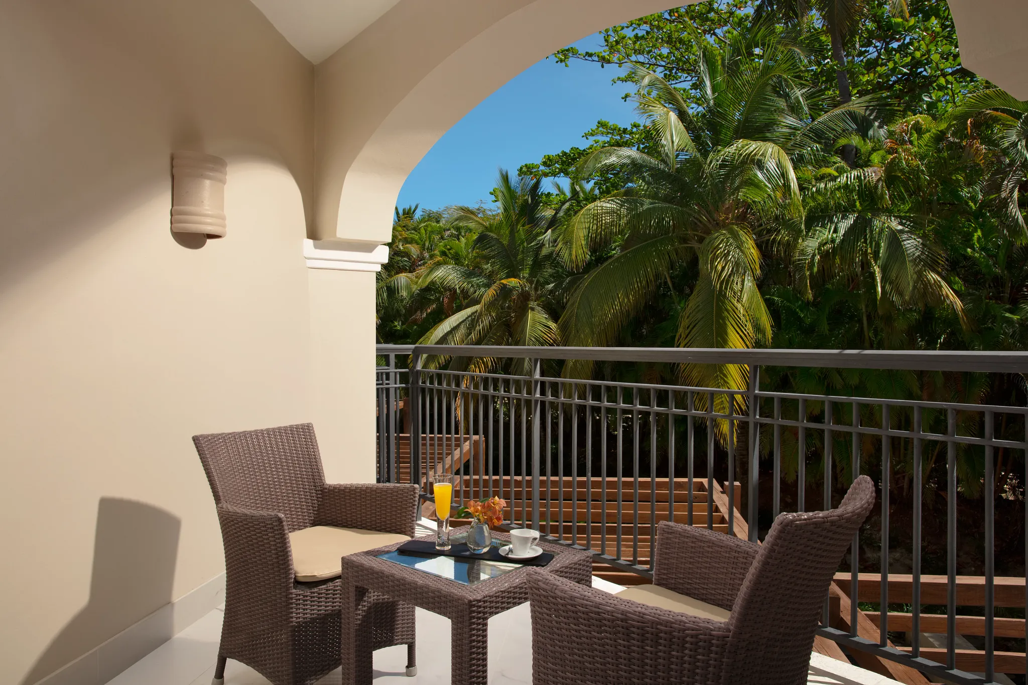Junior Suite private furnished balcony with tropical resort views at Secrets Royal Beach Punta Cana.