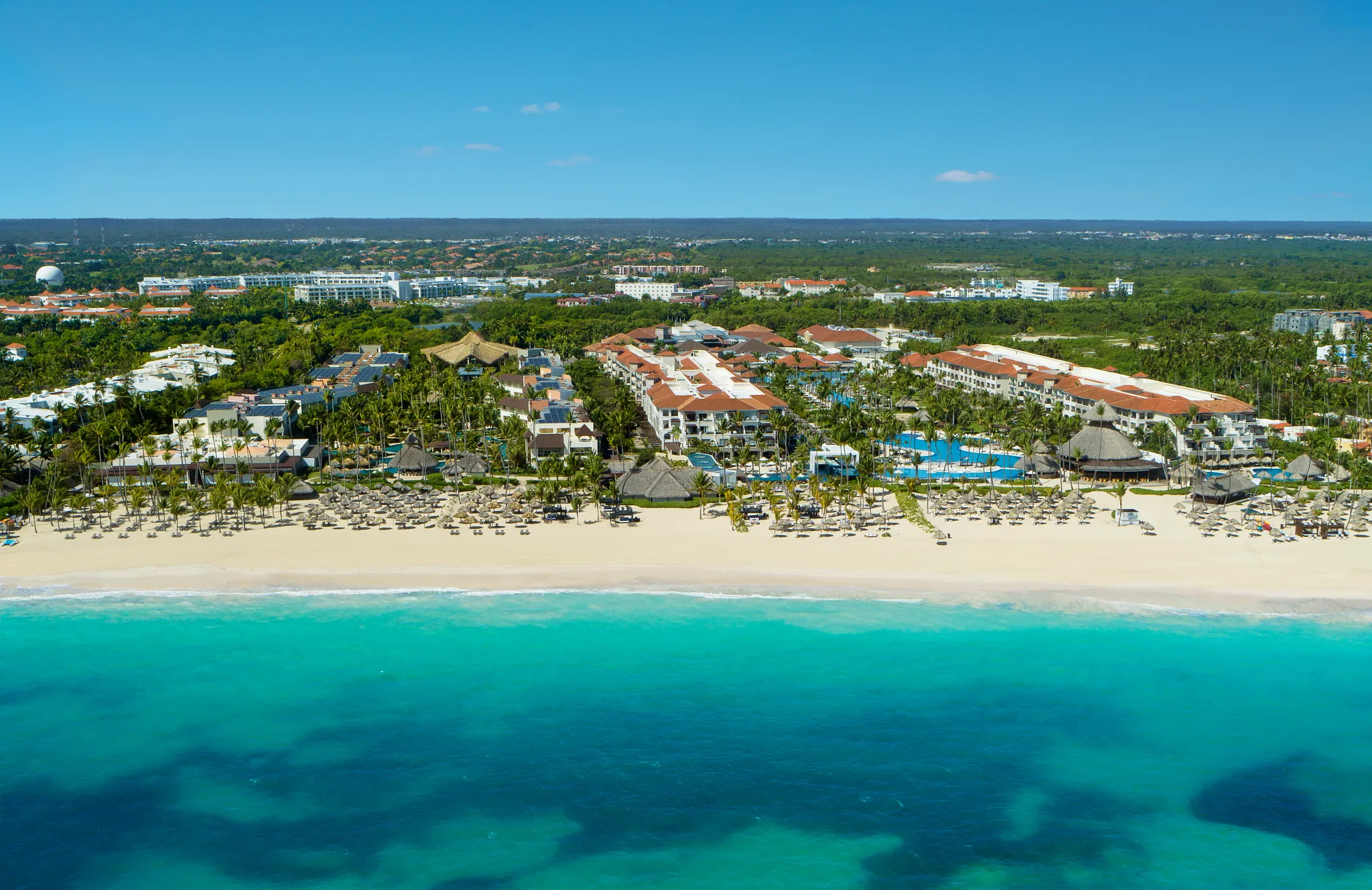 Aerial view of Secrets Royal Beach Punta Cana and Bavaro Beach with pools, palm trees, and white sand shoreline.