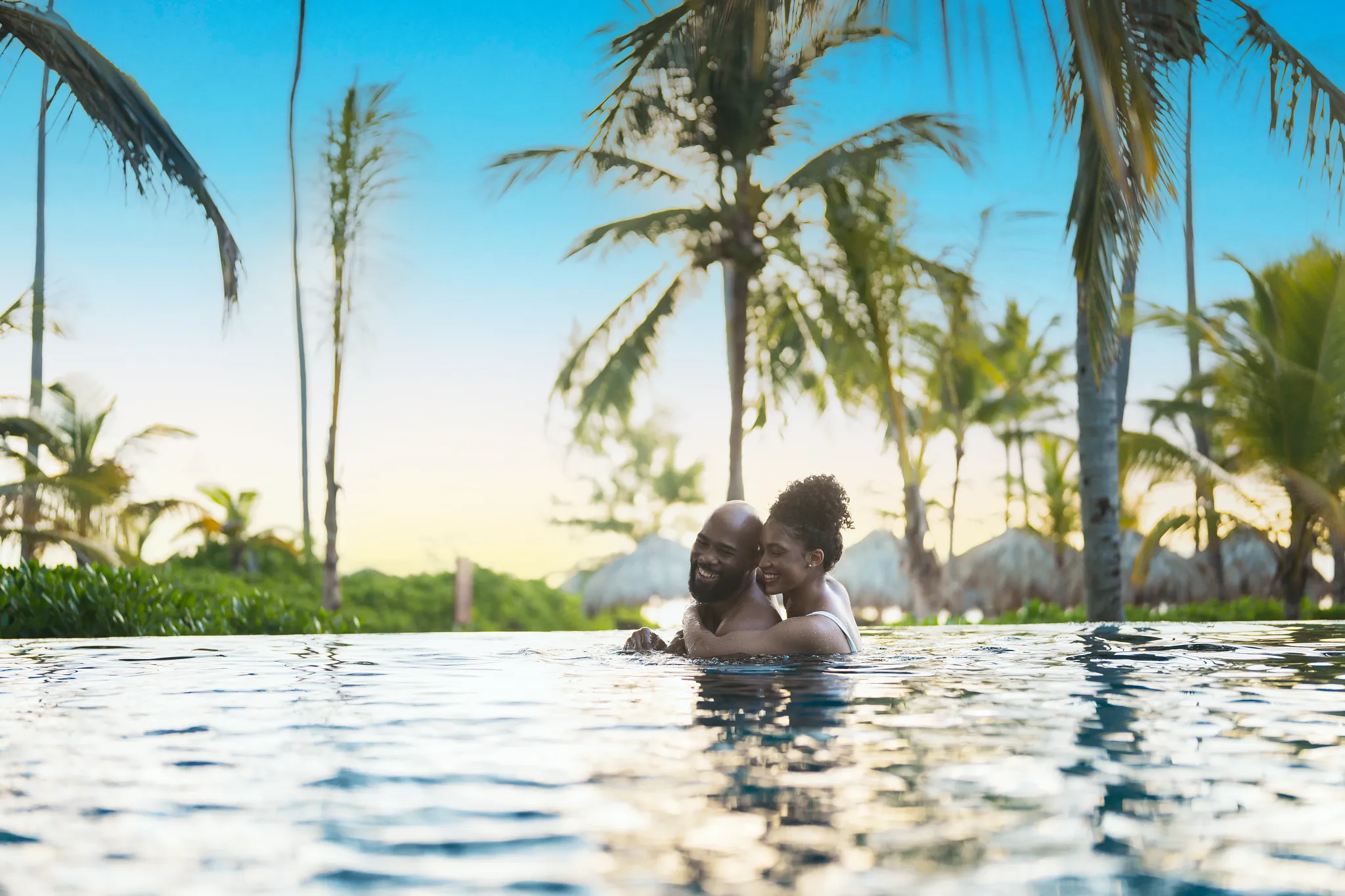 Romantic couple embracing in the infinity pool at sunset at Secrets Royal Beach Punta Cana.