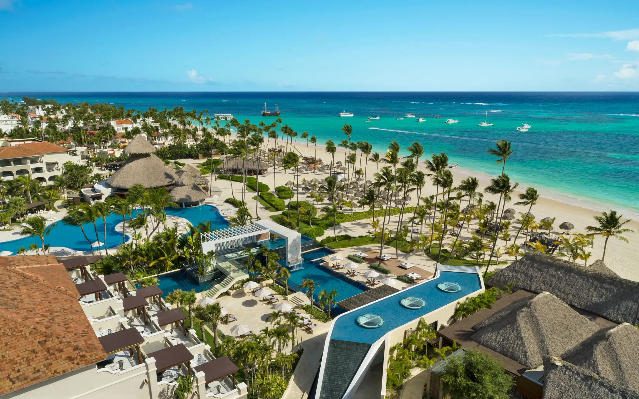 Elevated view of pools, beach loungers, and palm trees at Secrets Royal Beach Punta Cana resort.